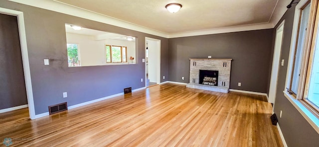 unfurnished living room with wood-type flooring, ornamental molding, and a fireplace