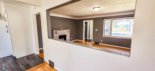 interior space with a stone fireplace, wood-type flooring, and a textured ceiling