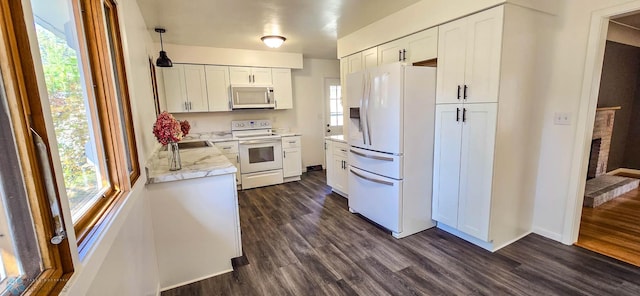 kitchen featuring white cabinets, hanging light fixtures, dark hardwood / wood-style floors, and white appliances