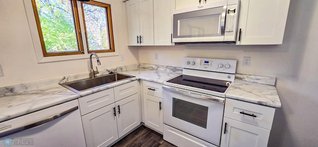 kitchen with sink, light stone countertops, white cabinets, white appliances, and dark hardwood / wood-style flooring