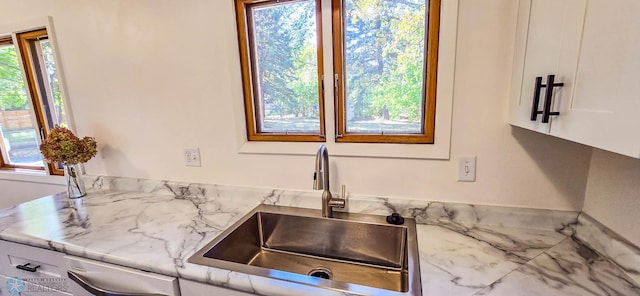 kitchen featuring light stone counters, sink, plenty of natural light, and white cabinets