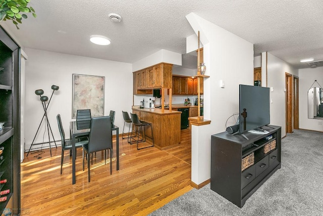 kitchen with a textured ceiling, a center island, light wood-type flooring, and a breakfast bar area