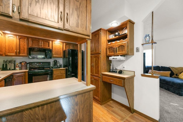 kitchen with light hardwood / wood-style floors, black appliances, and hanging light fixtures