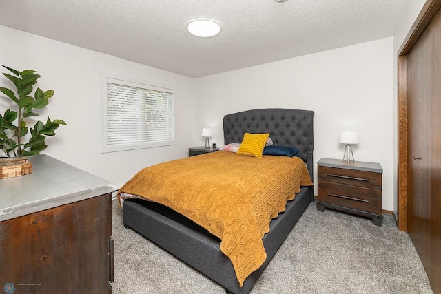 bedroom featuring a textured ceiling, light colored carpet, and a closet