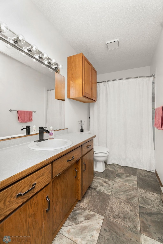 bathroom with vanity, a textured ceiling, and toilet