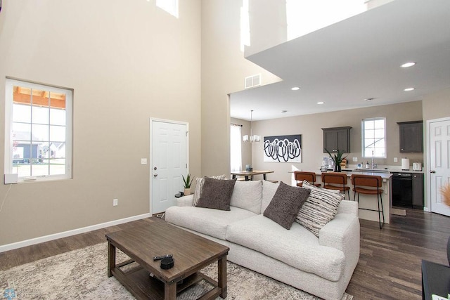 living room with a notable chandelier, a high ceiling, and dark hardwood / wood-style flooring