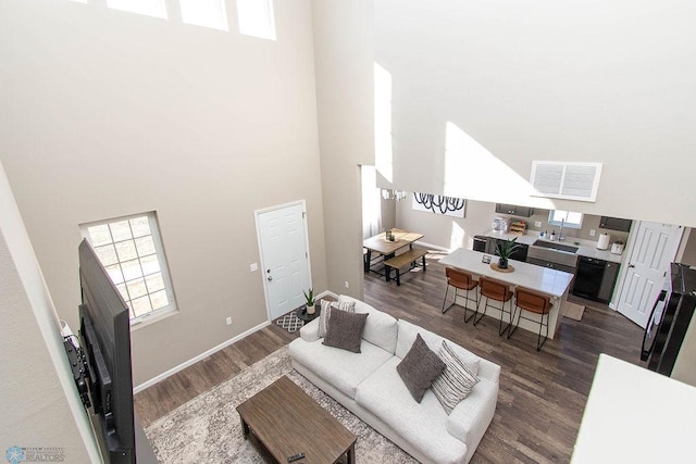 living room with sink, dark wood-type flooring, and a high ceiling