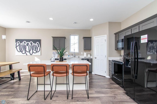 kitchen featuring black appliances, dark hardwood / wood-style flooring, a kitchen island, and gray cabinets