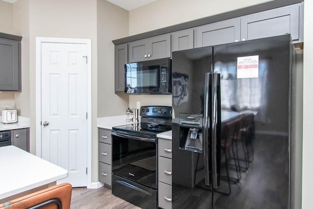 kitchen featuring hardwood / wood-style floors, black appliances, and gray cabinets