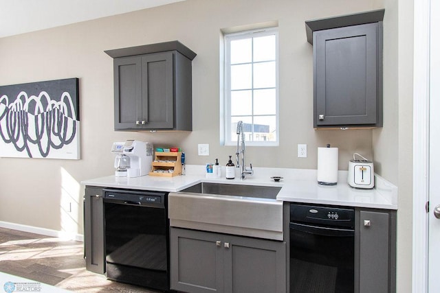 kitchen with gray cabinets, black dishwasher, sink, and light hardwood / wood-style flooring