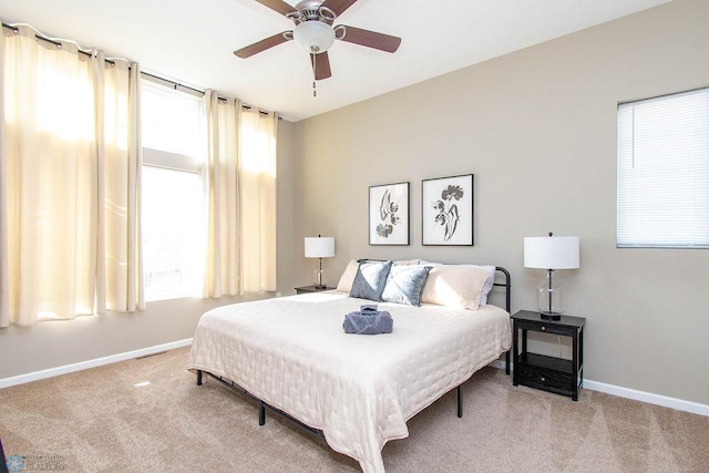 bedroom featuring multiple windows, light colored carpet, and ceiling fan