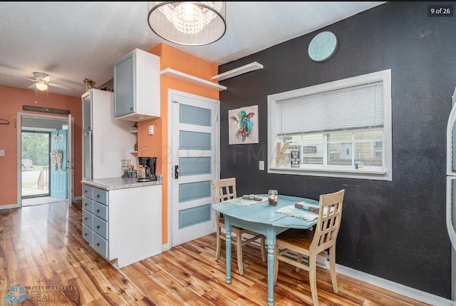 kitchen with light hardwood / wood-style flooring, white cabinetry, a textured ceiling, and ceiling fan