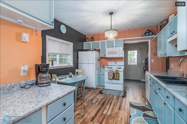 kitchen with light hardwood / wood-style flooring, sink, pendant lighting, blue cabinets, and white appliances