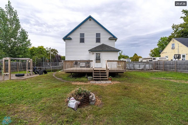 rear view of house featuring a deck, a yard, and a trampoline