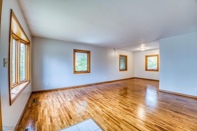 empty room with light hardwood / wood-style flooring and plenty of natural light