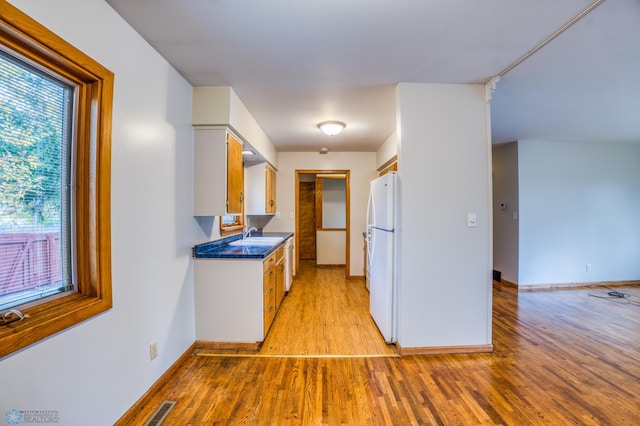 kitchen with white appliances, white cabinetry, light hardwood / wood-style flooring, and sink