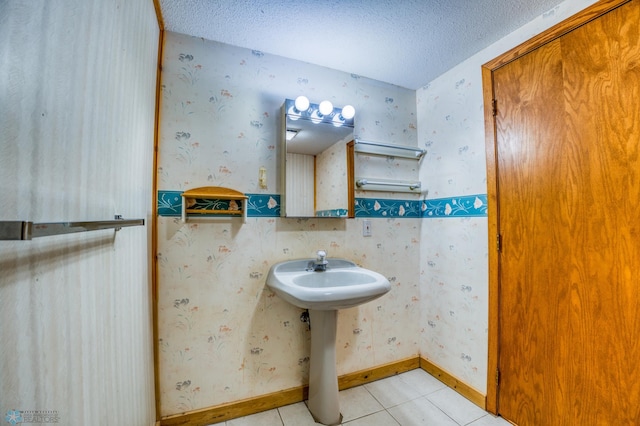 bathroom with a textured ceiling, sink, and tile patterned floors