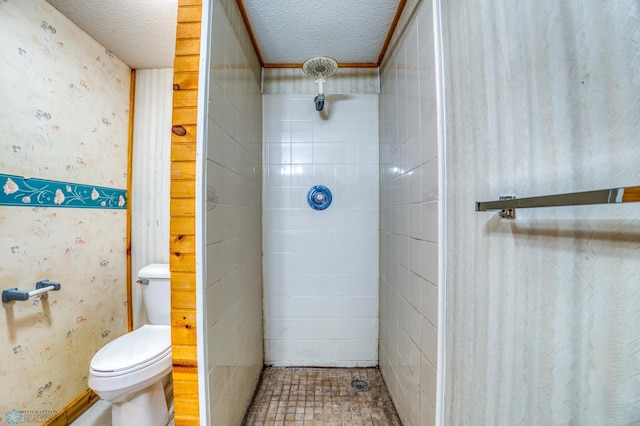 bathroom featuring toilet, a textured ceiling, and a tile shower