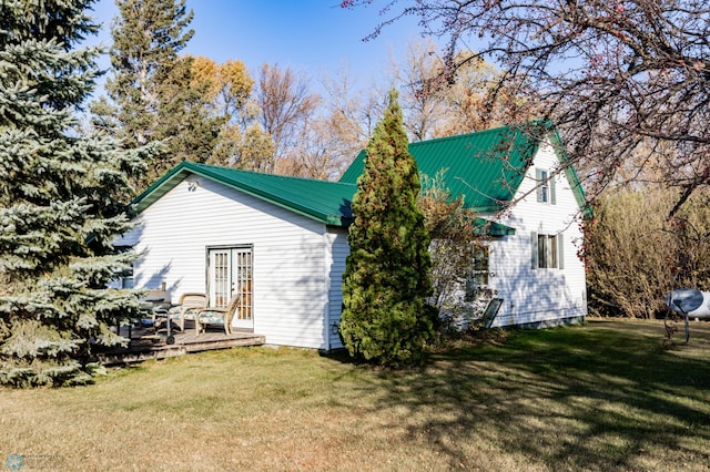 view of property exterior featuring french doors, a deck, and a lawn