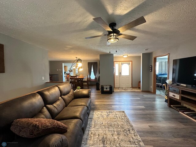 living room featuring a textured ceiling, dark wood-type flooring, and ceiling fan