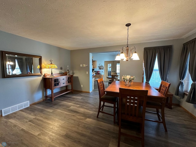 dining room featuring a notable chandelier, a textured ceiling, and dark hardwood / wood-style flooring