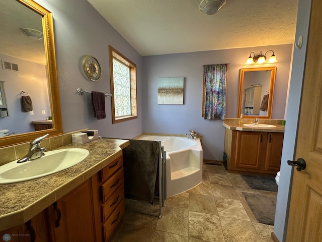 bathroom featuring vanity, a textured ceiling, and a tub to relax in