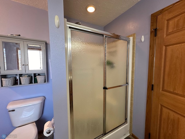 bathroom with a shower with shower door, a textured ceiling, and toilet