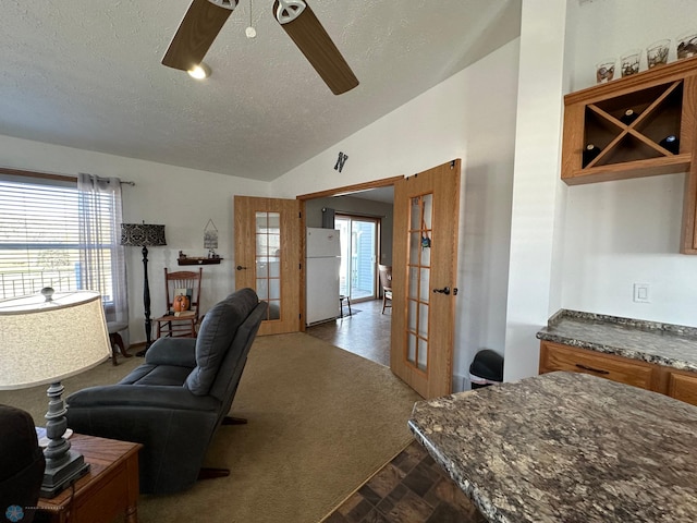 living room with ceiling fan, a textured ceiling, vaulted ceiling, and plenty of natural light