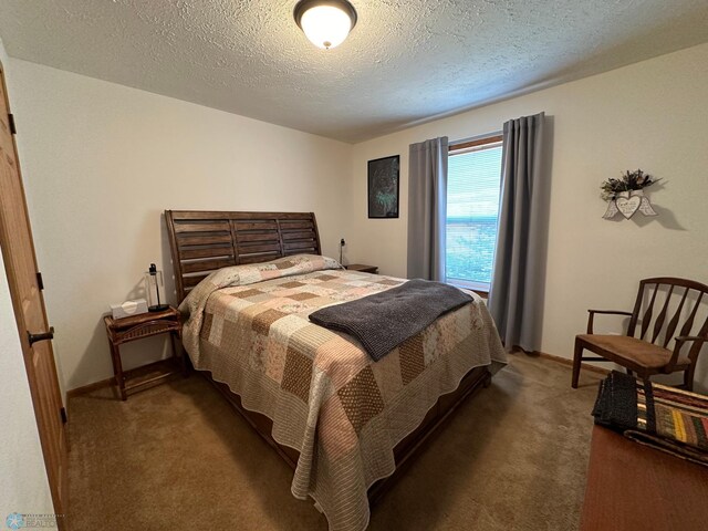 bedroom with a textured ceiling and dark carpet