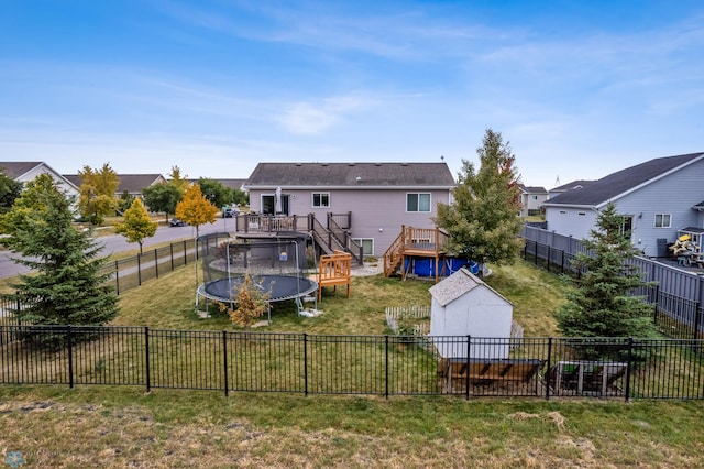 back of house featuring an outdoor structure, a deck, and a lawn