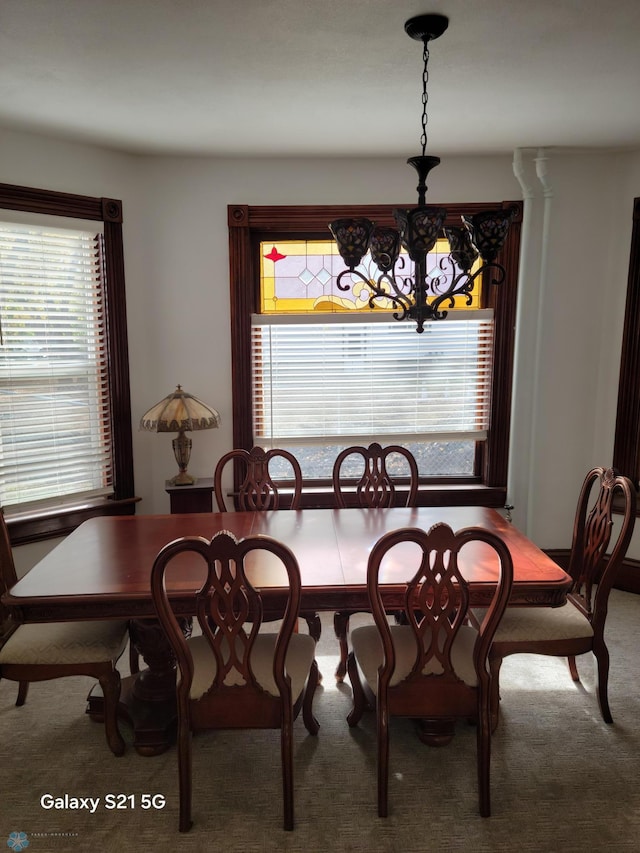 carpeted dining space featuring a notable chandelier