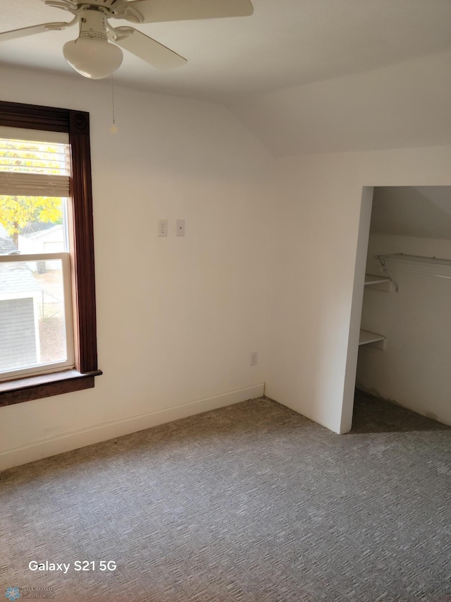 unfurnished bedroom featuring a closet, ceiling fan, carpet, and vaulted ceiling