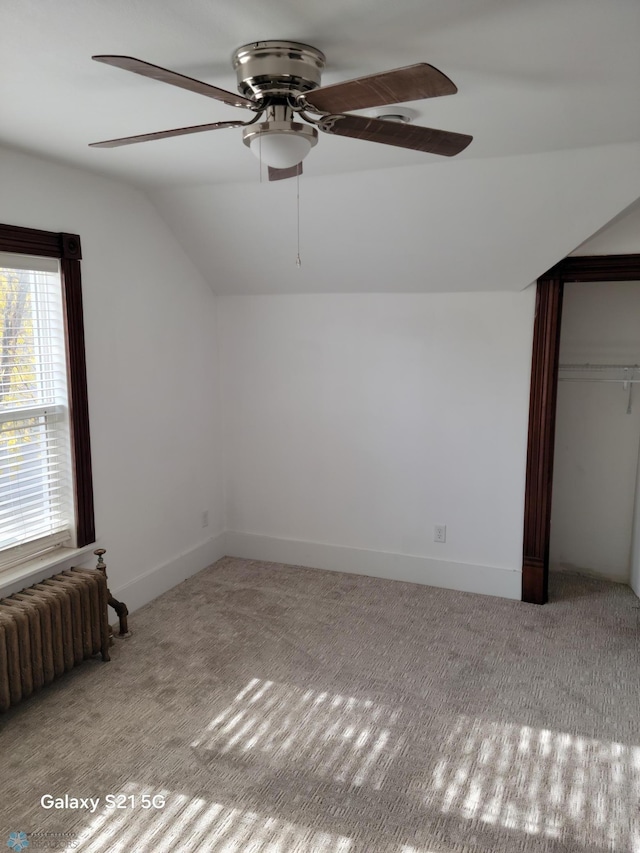 additional living space with lofted ceiling, light colored carpet, radiator, and ceiling fan