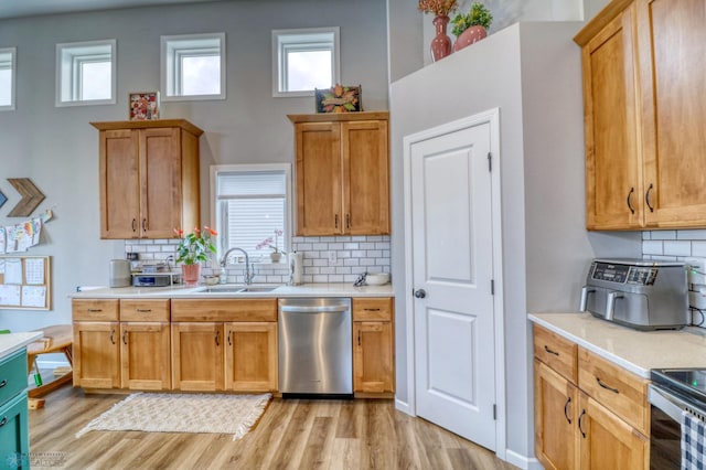 kitchen featuring appliances with stainless steel finishes, sink, light wood-type flooring, and decorative backsplash