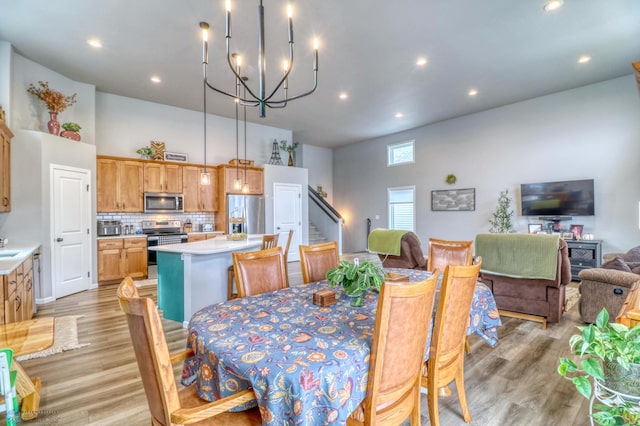 dining area with sink, a chandelier, light wood-type flooring, and a high ceiling