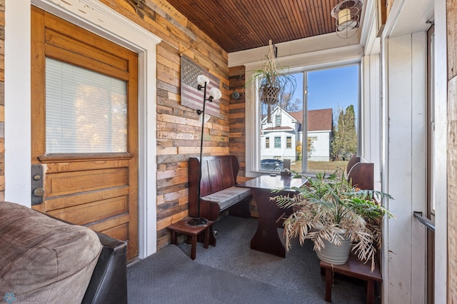 living area featuring wooden walls, carpet flooring, and wooden ceiling