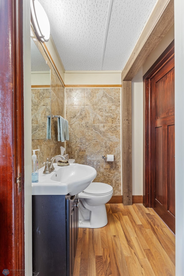 bathroom featuring tile walls, vanity, hardwood / wood-style flooring, and toilet