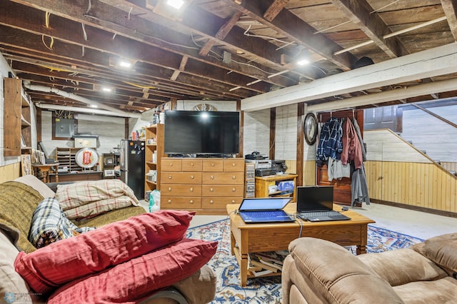 living room with wood walls, electric panel, and concrete flooring