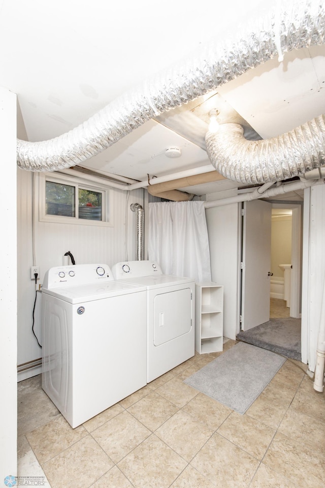 laundry room featuring wooden walls, light tile patterned flooring, and washer and dryer