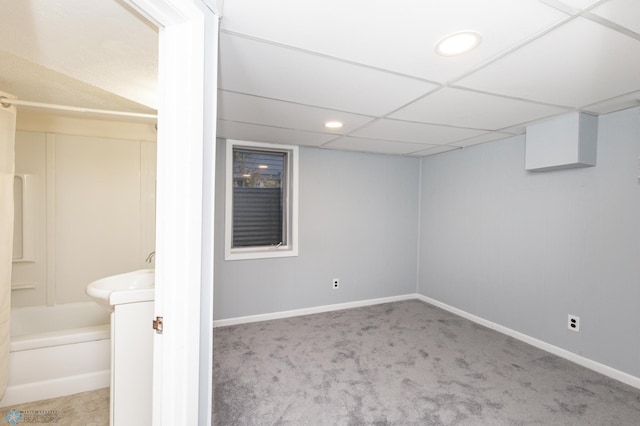 basement featuring a drop ceiling and light colored carpet