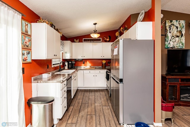 kitchen with white cabinetry, stainless steel refrigerator, and vaulted ceiling