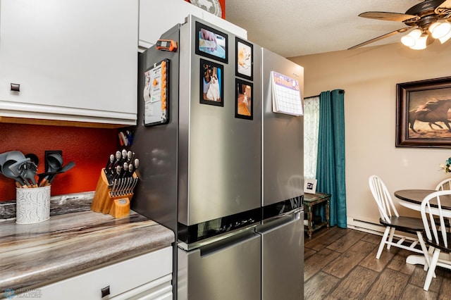 kitchen featuring white cabinets, stainless steel fridge, ceiling fan, dark hardwood / wood-style flooring, and a textured ceiling