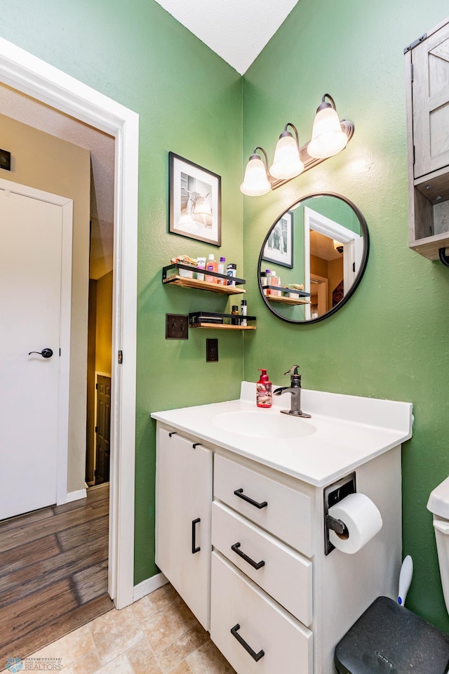 bathroom with vanity, toilet, and hardwood / wood-style flooring