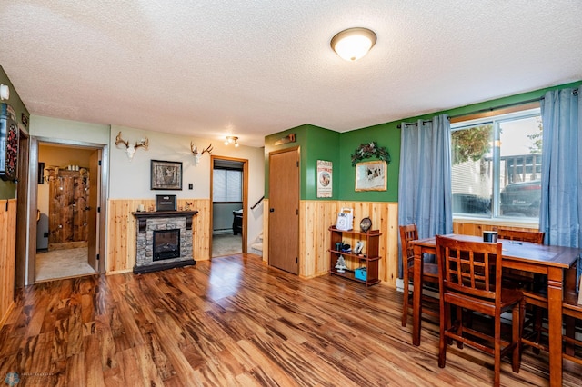 dining space with wood walls, a textured ceiling, and hardwood / wood-style flooring