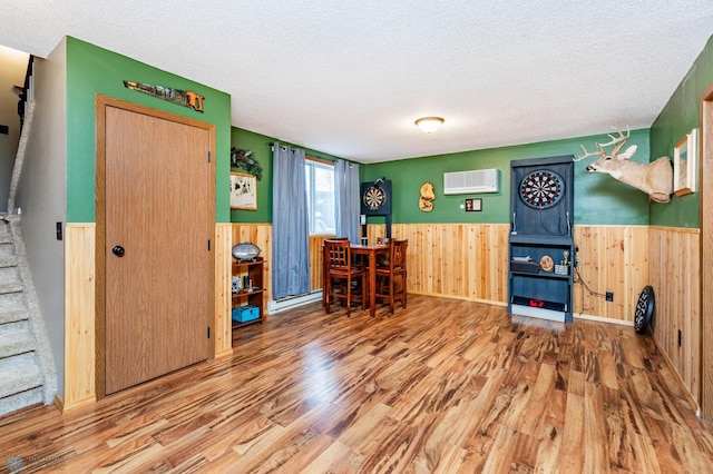 interior space featuring wooden walls, wood-type flooring, a textured ceiling, and a wall mounted air conditioner