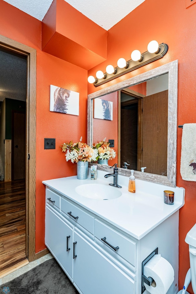 bathroom featuring toilet, a textured ceiling, and vanity