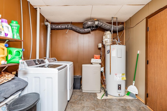 clothes washing area featuring electric water heater, wooden walls, and washing machine and clothes dryer