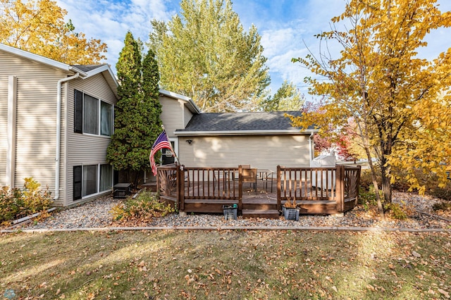 rear view of property featuring a wooden deck and a lawn