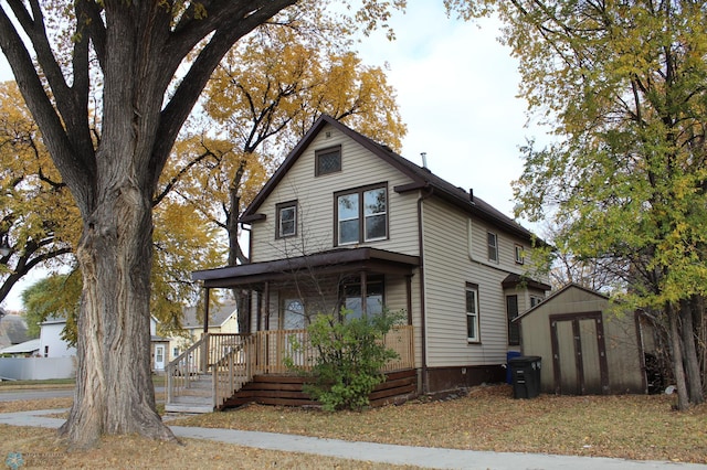 view of front of home featuring a porch and a storage unit