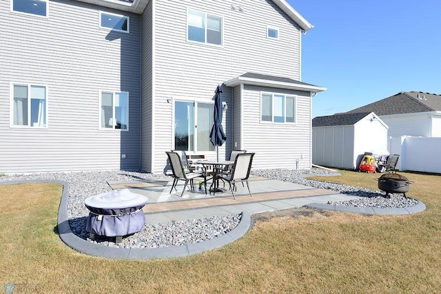 rear view of house featuring an outdoor fire pit, a patio area, a storage unit, and a lawn